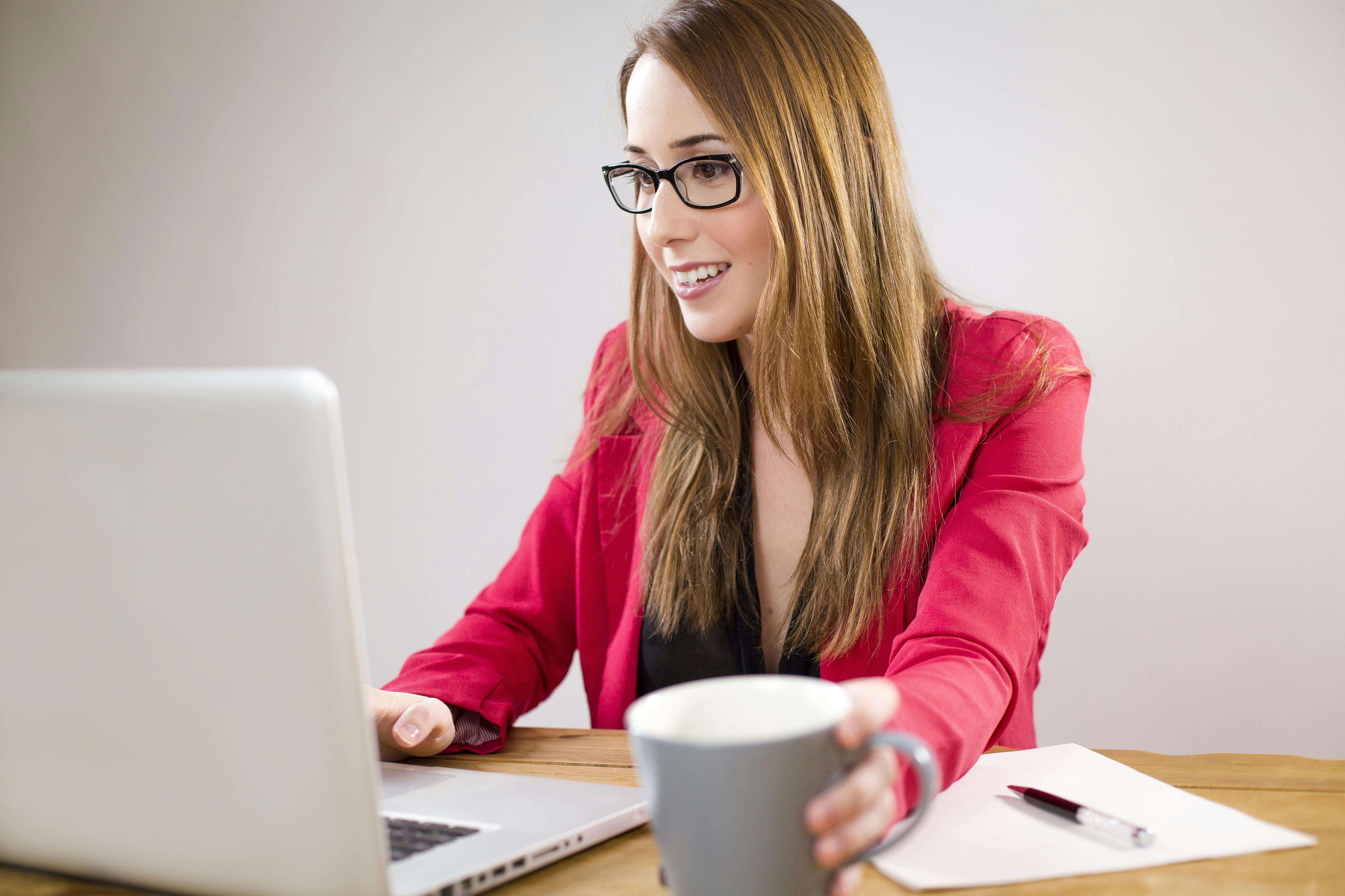 woman working on coumputer grabing a cofee